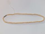 gros plan d'un collier de perles sur une surface blanche