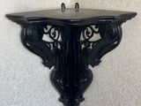 une étagère noire fixée au mur, dans un coin de la pièce