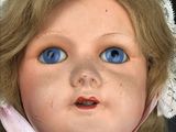 a close up of a doll with blue eyes and a pink scarf