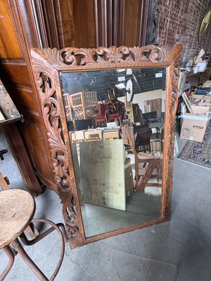a large mirror sitting on the floor next to a chair