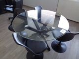 une table en verre avec des chaises et un ordinateur portable posé dessus