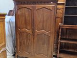 une armoire en bois placée dans un coin de la pièce, à côté d'un lit