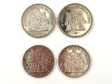 four different types of silver coins on a white surface