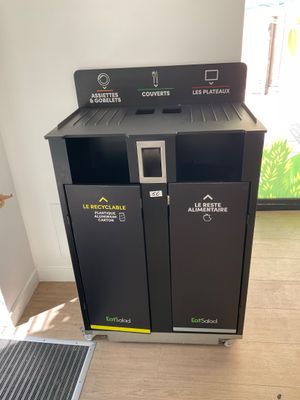 two black trash bins in the corner of a room