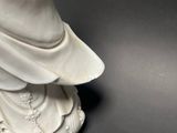 a statue of a woman in a white dress on a black surface