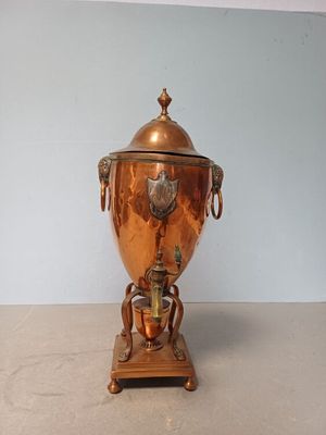 a large copper urn sitting on a wooden stand