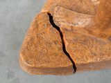 a sculpture of a person sitting on top of a piece of wood