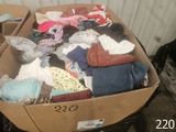 une boîte en carton remplie de vêtements posée par terre