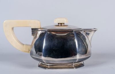 une théière ancienne en argent, munie d'une poignée en bois et posée sur un socle