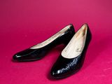 a pair of black shoes sitting on top of a pink surface