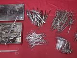 many different types of sewing needles on a red table
