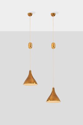 a pair of brass colored pendant lights hanging from a ceiling