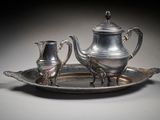 a silver plate with a silver tea pot and a silver cup on it