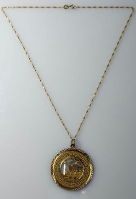 a gold necklace with a coin on a chain