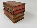 three old books stacked on top of each other on a white surface