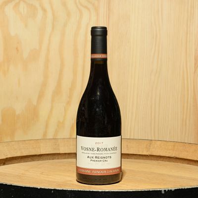a bottle of wine sitting on top of a barrel