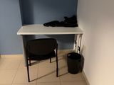 a desk with a chair and a trash can in the corner of the room