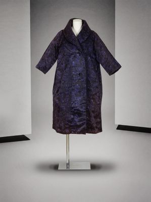 une photo d'un manteau violet posé sur un portant dans une pièce