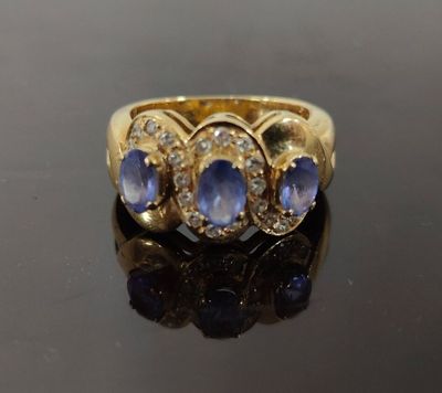gros plan d'une bague en or avec saphirs bleus et diamants
