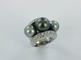 une bague en perle noire et diamants sur fond blanc