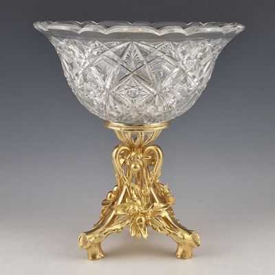 a glass bowl on a gold stand on a gray background