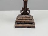 a statue of a man holding a cross on top of a table