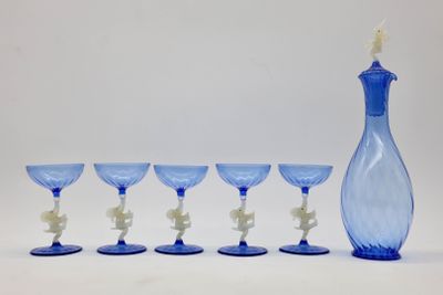 six verres à vin bleus et un vase bleu posés sur une table blanche
