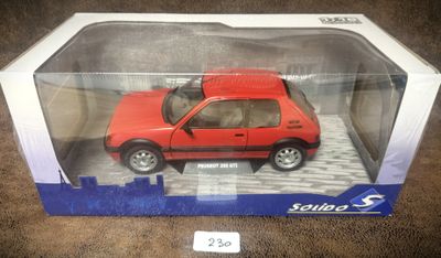 une petite voiture rouge dans une boîte en plastique transparent, posée sur un tapis marron