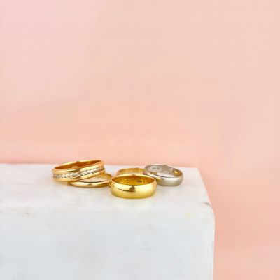 une pile de trois bagues en or et en argent posée sur un bloc de marbre