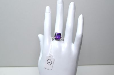la main de quelqu'un tenant une bague sertie d'une pierre violette