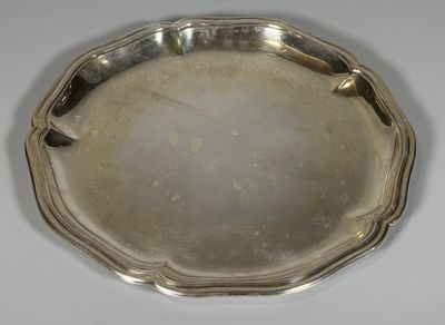 un plat en argent ancien posé sur une table blanche, sur fond blanc