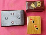 trois boîtes en bois ornées de cartes à jouer, posées sur un fond rose