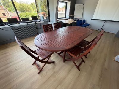 une table et des chaises en bois dans une pièce dotée de grandes fenêtres