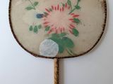 a fan with a painting on it hanging on a wall