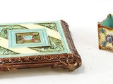 une petite boîte et un petit vase posés sur une surface blanche