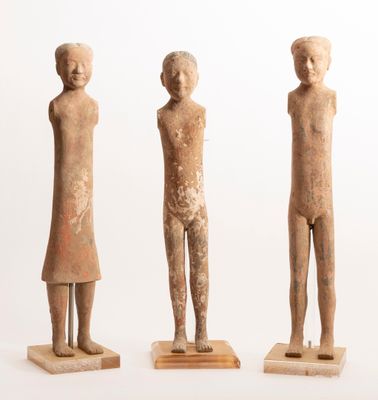 three figurines of a man and a woman standing on wooden bases