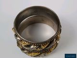 a close up of a silver and gold bracelet on a white surface