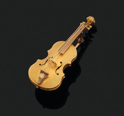 une broche en forme de violon dorée sur un fond noir
