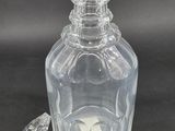 a clear glass bottle with a stopper next to it