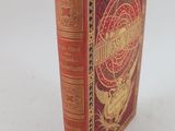 un vieux livre à la couverture rouge posé sur une table blanche