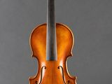 an old violin sitting on a stand against a gray background