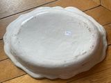 a white plate sitting on a wooden floor with a sticker on it