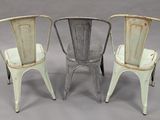 three metal chairs sitting next to each other on a gray surface
