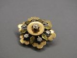 une image représentant une broche en or et diamants posée sur une surface grise