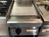 Plusieurs cuisinières en acier inoxydable sont alignées dans une cuisine
