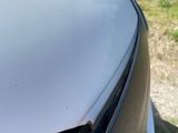 someone is removing the hood of a white car with their hand