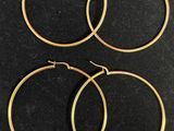trois paires de boucles d'oreilles créoles en or sur un fond noir