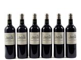 six bottles of wine are lined up in a row on a white surface