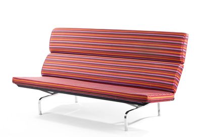 canapé-futon rayé avec des pieds en métal et un coussin rouge