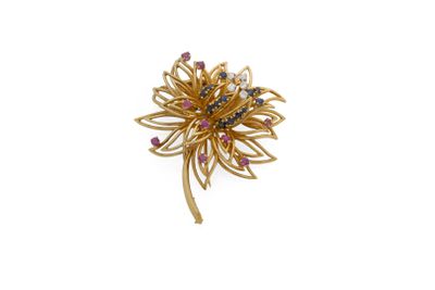 un gros plan sur une broche en or sertie de pierres roses et bleues